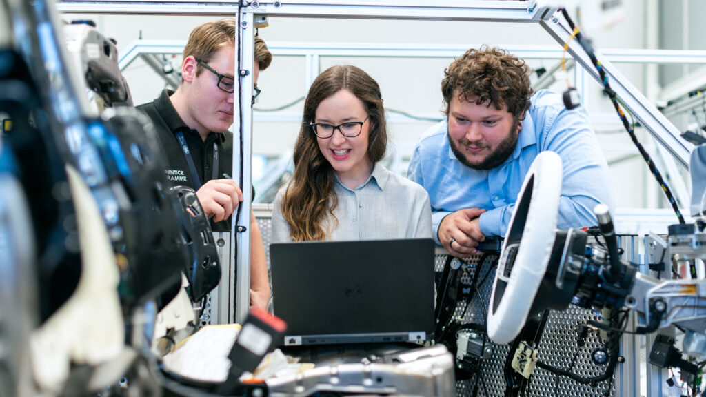 Frau in der Mechatronik zusammen mit männlichen Kollegen vor Computer